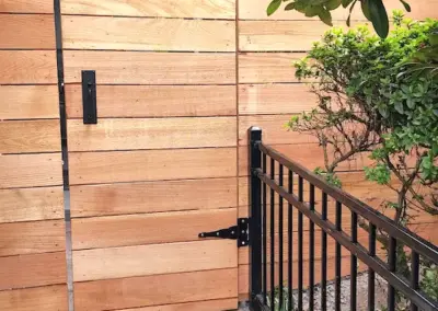 Custom horizontal wood fence gate installation in Seattle with black metal hardware