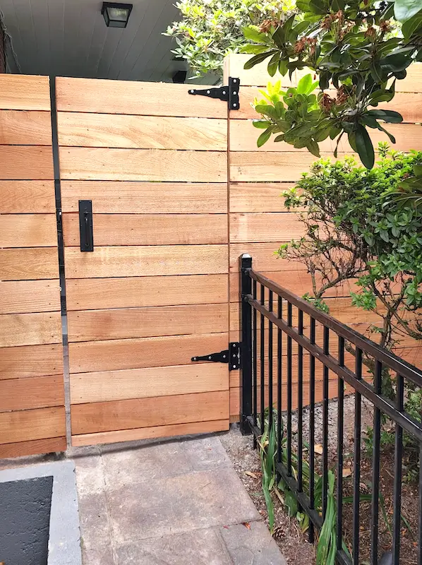 Custom horizontal wood fence gate installation in Seattle with black metal hardware