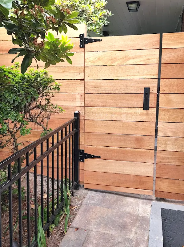 Custom horizontal wood fence gate installation in Seattle with black metal hardware