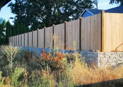 Wood privacy fence installation in Seattle with cedar panels and concrete retaining wall