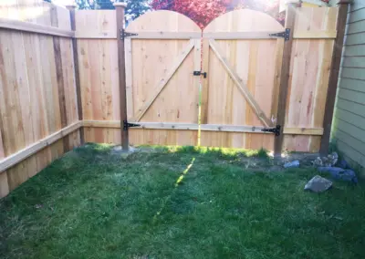 Custom double wooden gate installation in Seattle with cedar fence and black metal hardware