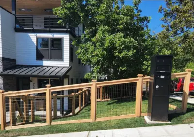 Wood and wire fence installation in front of modern residential home