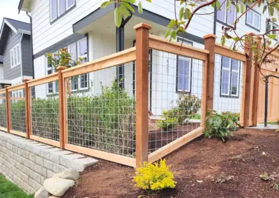 Residential wood fence with wire mesh panels and landscaping