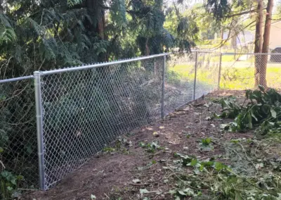 Galvanized chain link fence installed along wooded property line