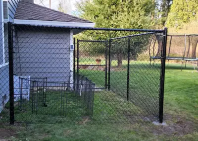 Black chain link fence installation in residential backyard with secure gate