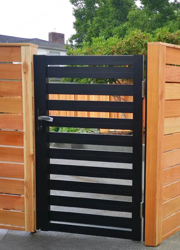 Modern black metal gate integrated into a wooden fence, front view<br />
